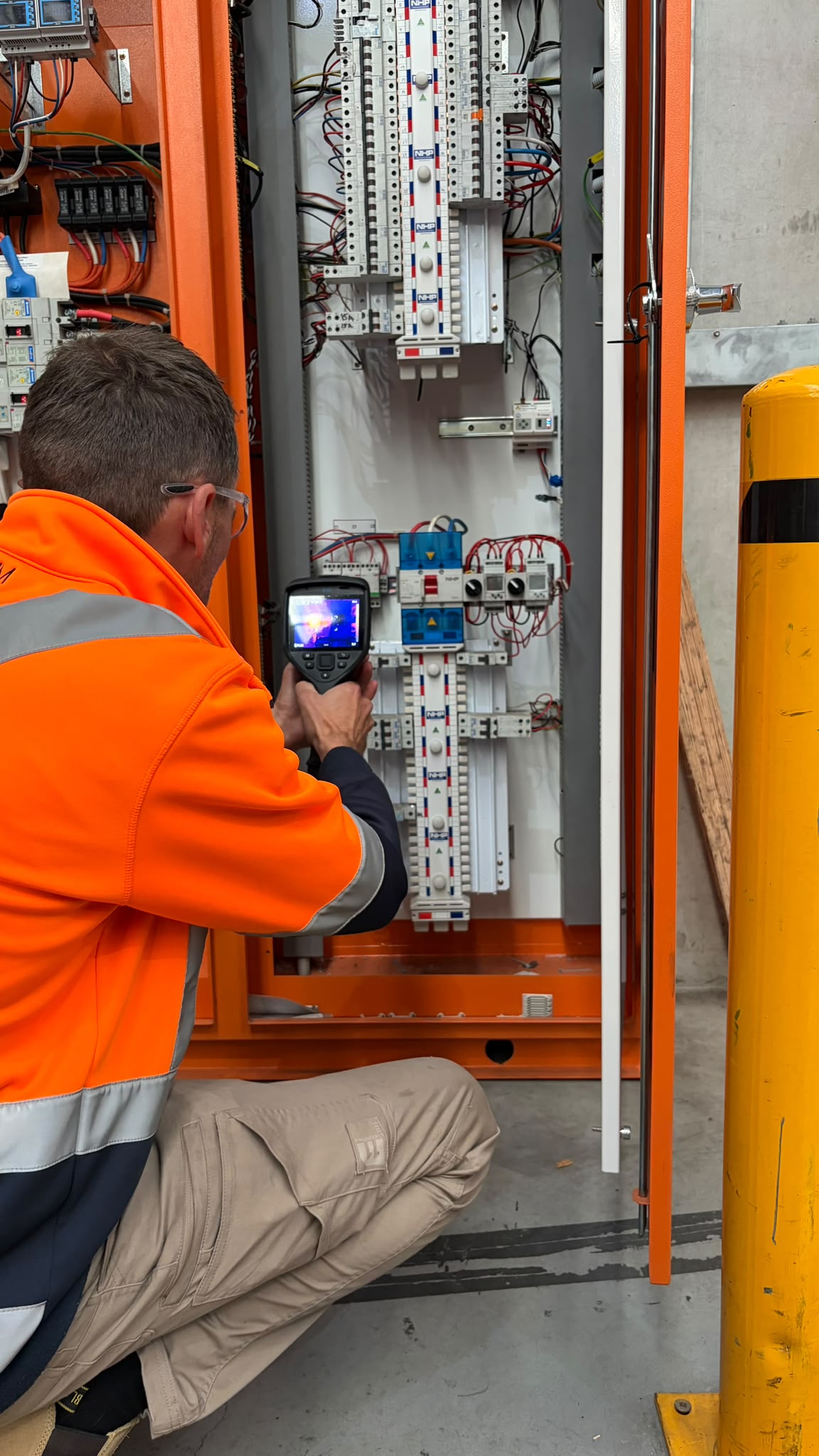 Technician performing switchboard thermal imaging inspection